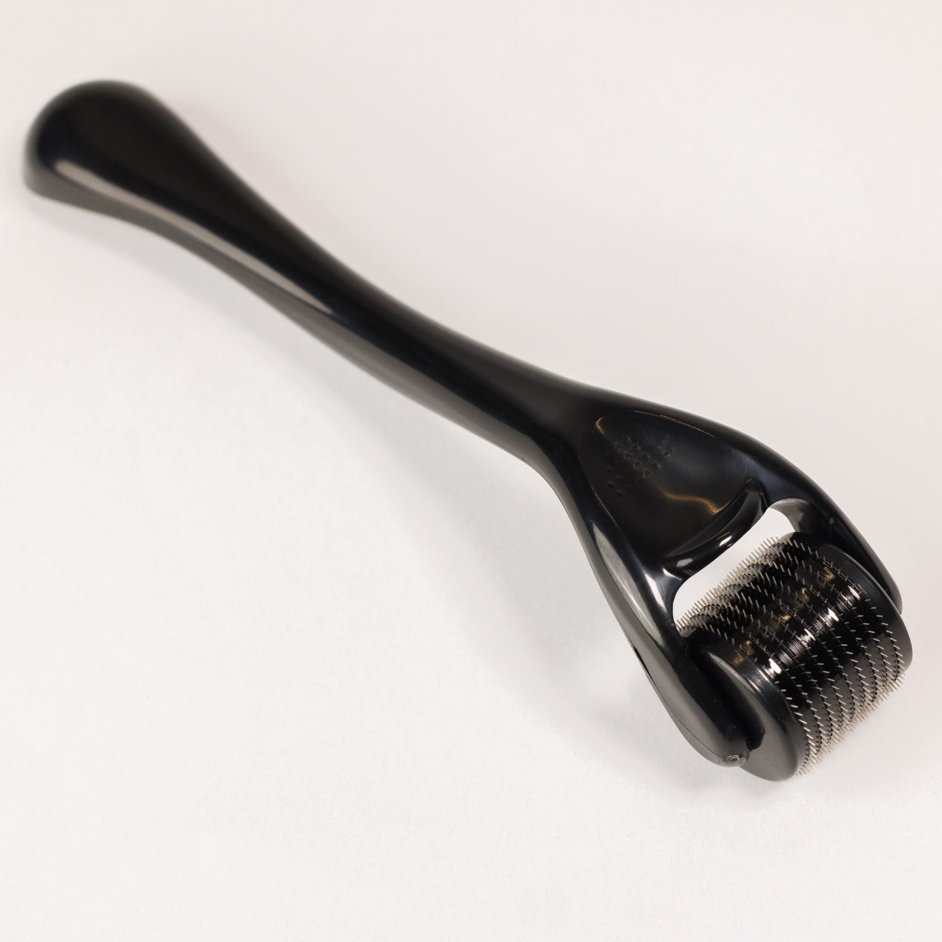 Der Dr. Balwi Dermaroller von Dr. Balwi Shop ist ein schwarzes Microneedling-Tool mit nadelbesetztem Roller und langem Griff - perfekt für die Hautverjüngung und zur Unterstützung des Haarwachstums, dargestellt auf einer schlichten weißen Oberfläche.