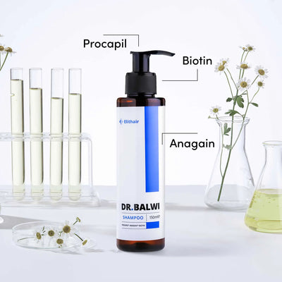 Eine Flasche der Anti-Haarausfall-Routine von Dr. Balwi Shop ist auf einer weißen Fläche mit Blumen und Glaslaborgeräten im Hintergrund abgebildet. Die Etiketten heben die wichtigsten Inhaltsstoffe hervor: Procapil, Biotin und Anagain.
