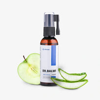 Eine braune Flasche Dr. Balwi Hair Serum aus dem Dr. Balwi Shop mit Sprühkopf ist neben einem aufgeschnittenen grünen Apfel und Aloe Vera Blättern auf weißem Hintergrund abgebildet und unterstreicht die natürlichen Lösungen bei Haarausfall.